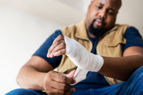 man with an injured hand wrapping it with gauze
