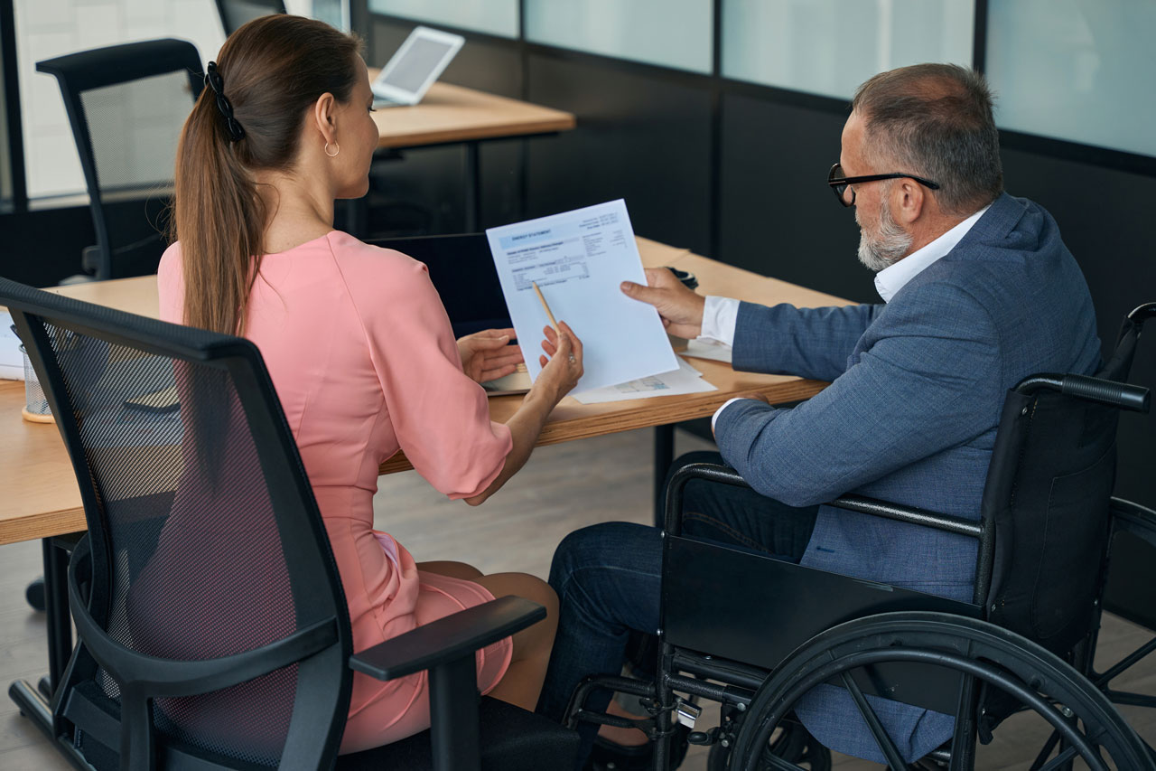 An attorney is speaking to someone in a wheelchair looking for legal representation