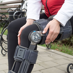 A person in a leg brace sitting on a bench